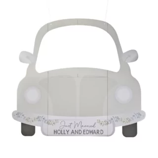 Photobooth in de vorm van een sagegroene auto met bloemen op de bumper en personaliseerbare namen