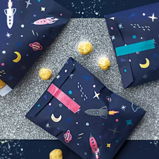 Donkerblauw tafelkleed met zilveren tafelloper met glitters en donkerblauwe snoepzakjes met sterren en raketten erop