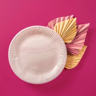 Roze marmeren bordje op een roze achtergornd met lichtroze en gouden papieren palmbladeren