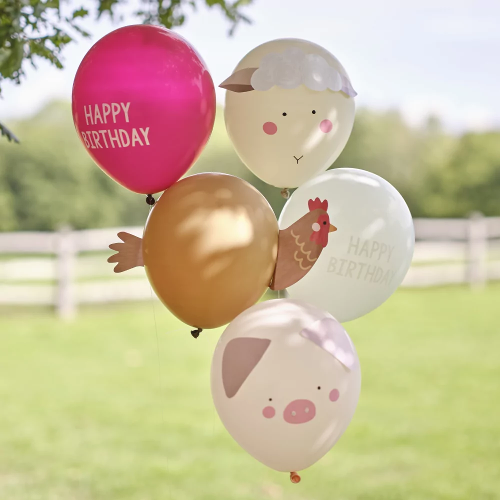 Ballonnen met de tekst happy birthday en een varken, een kip en een schaap hangen onder een boom in de schaduw