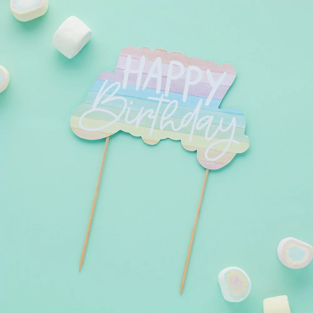 Taart topper met de tekst happy birthday in pasteltinten op een lichtblauwe achtergrond