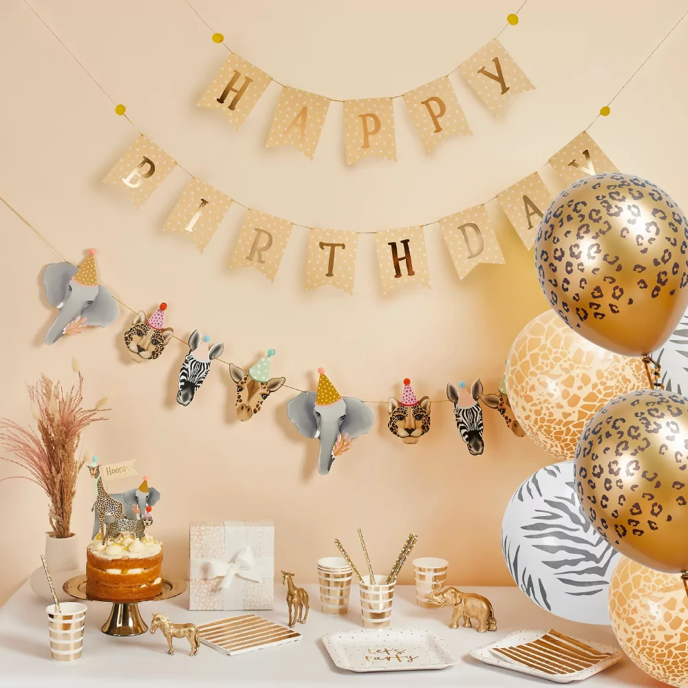 Gele muur versierd met gele en gouden slinger, een slinger met jungle dieren en ballonnen met dierenprint