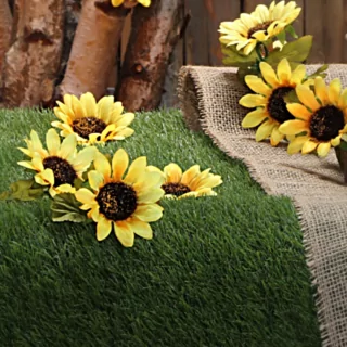 Zonnebloemen op een groen grasveld naast een jute tafelloper