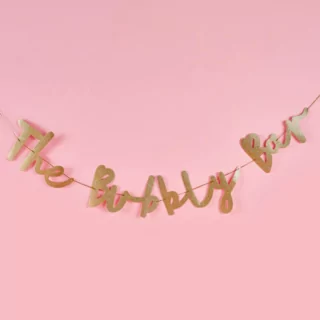 Gouden glitterslinger voor een roze achtergrond met de tekst the bubbly bar