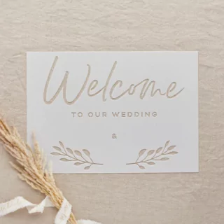 transparant stencil met de tekst welcome to our wedding op een jute achtergrond met graan