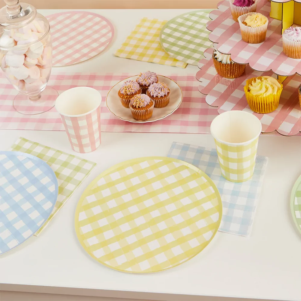 tafel versierd met geblokte items zoals servetten, bordjes en bekers in het geel, groen, roze en blauw