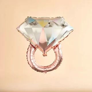 Rose gouden folieballon in de vorm van een ring op een perzikkleurige achtergrond