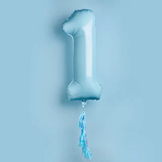 Babyblauwe ballon cijfer 1 met een tassel zweeft voor een blauwe muur
