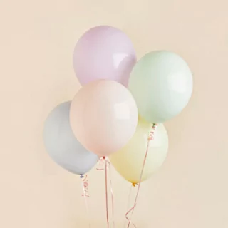 ballonnen in pasteltinten paars, groen, blauw, oranje en geel voor een zalmkleurige muur