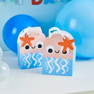 Cadeautasjes in de vorm van een zachtroze kwal met blauwe vinnen en een oranje zeester staan op een witte tafel voor een blauw ballon