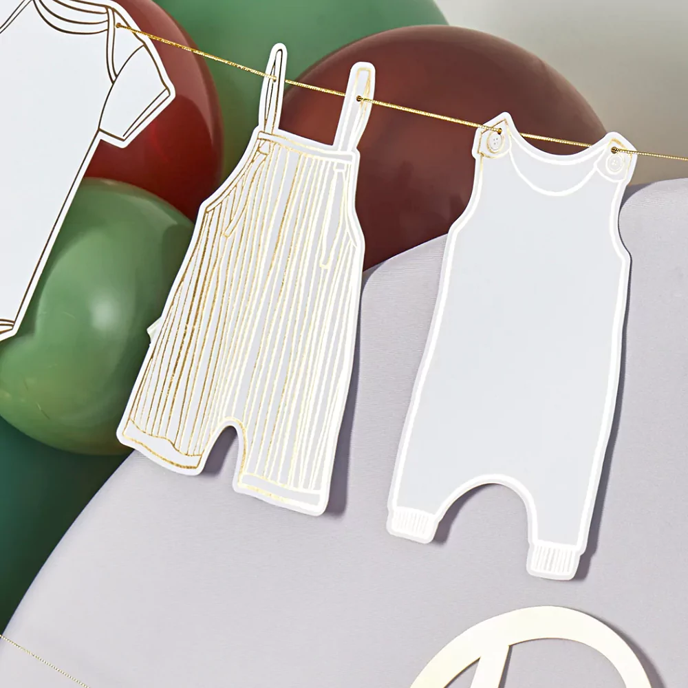 Slinger met rompertjes in het grijs en wit met gouden details hangt voor een groene en bruine ballonnenboog