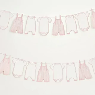 Slinger met roze en witte rompertjes hangt voor een lichtgrijze muur