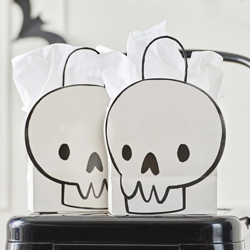 Cadeautasje met een doodshoofd erop in het zwart en wit staat op een zwarte kruk en is gevuld met wit tissuepapier