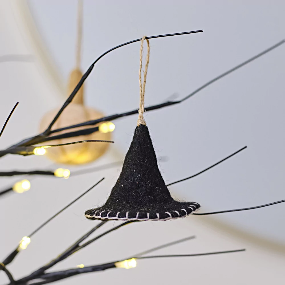 Zwarte heksenhoed van vilt hangt aan een lichtgevende, zwarte boom