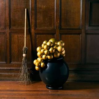 Heksenketel met bubbels in het zwart en goud staat voor een houten muur