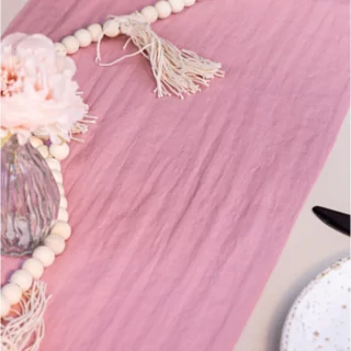 Roze tafelloper ligt op een tafel versierd met rozen en kralenslingers