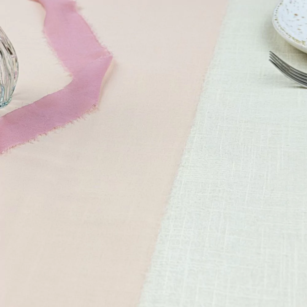 Poeder roze tafelloper ligt op een wit kleed van katoen