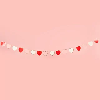 Slinger met roze, rode en witte hartjes hangt voor een roze muur
