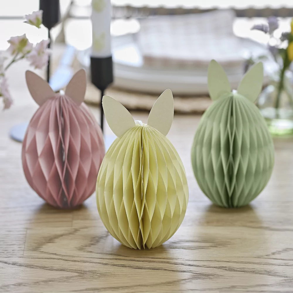 Papieren paaseieren met konijnenoren staan op een houten tafel