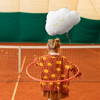 meisje op een tennisbaan met een wolk ballon