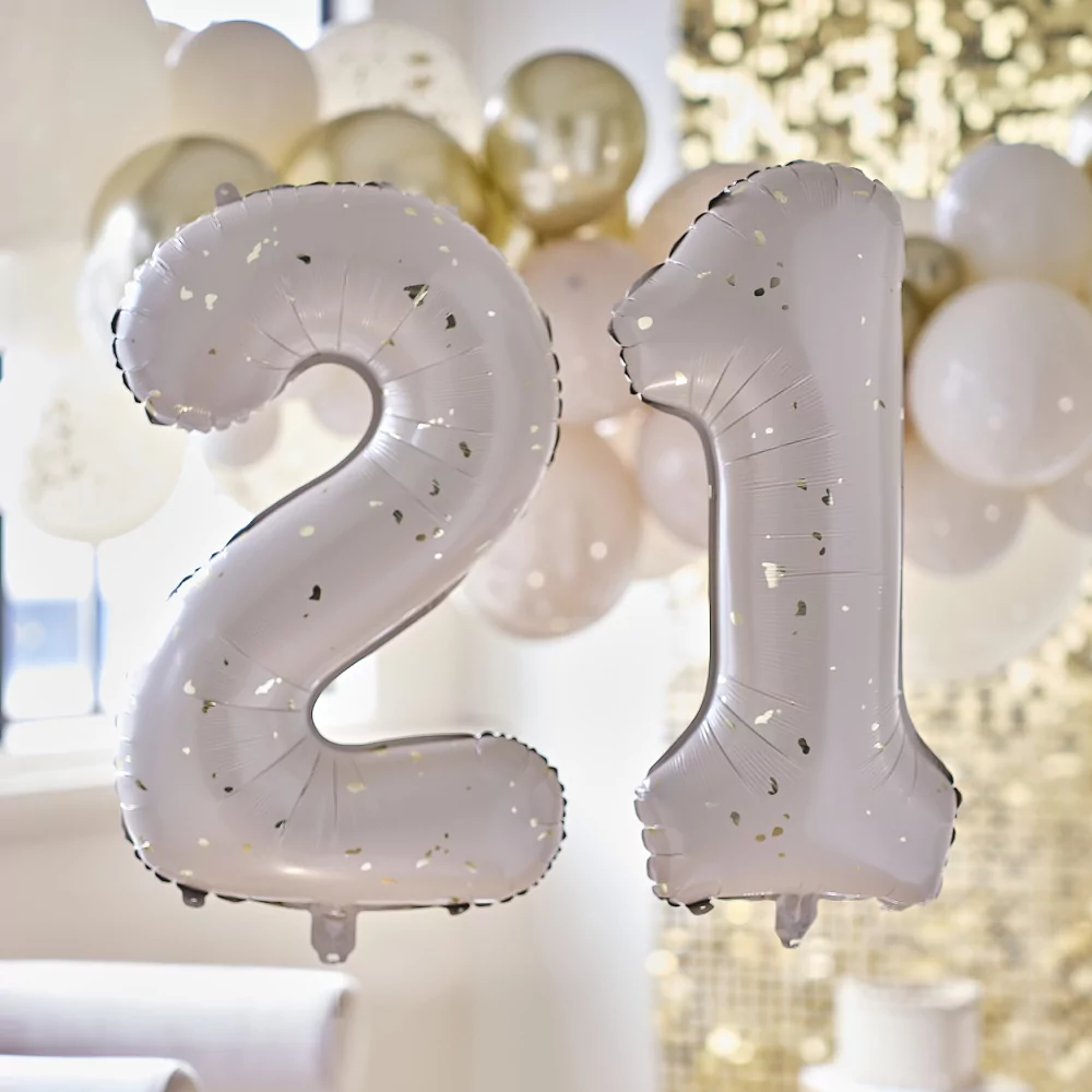 Cijferballonnen 21 in het nude met gouden spikkels voor een versierde woonkamer met gouden bakcdrop en ballonnenboog