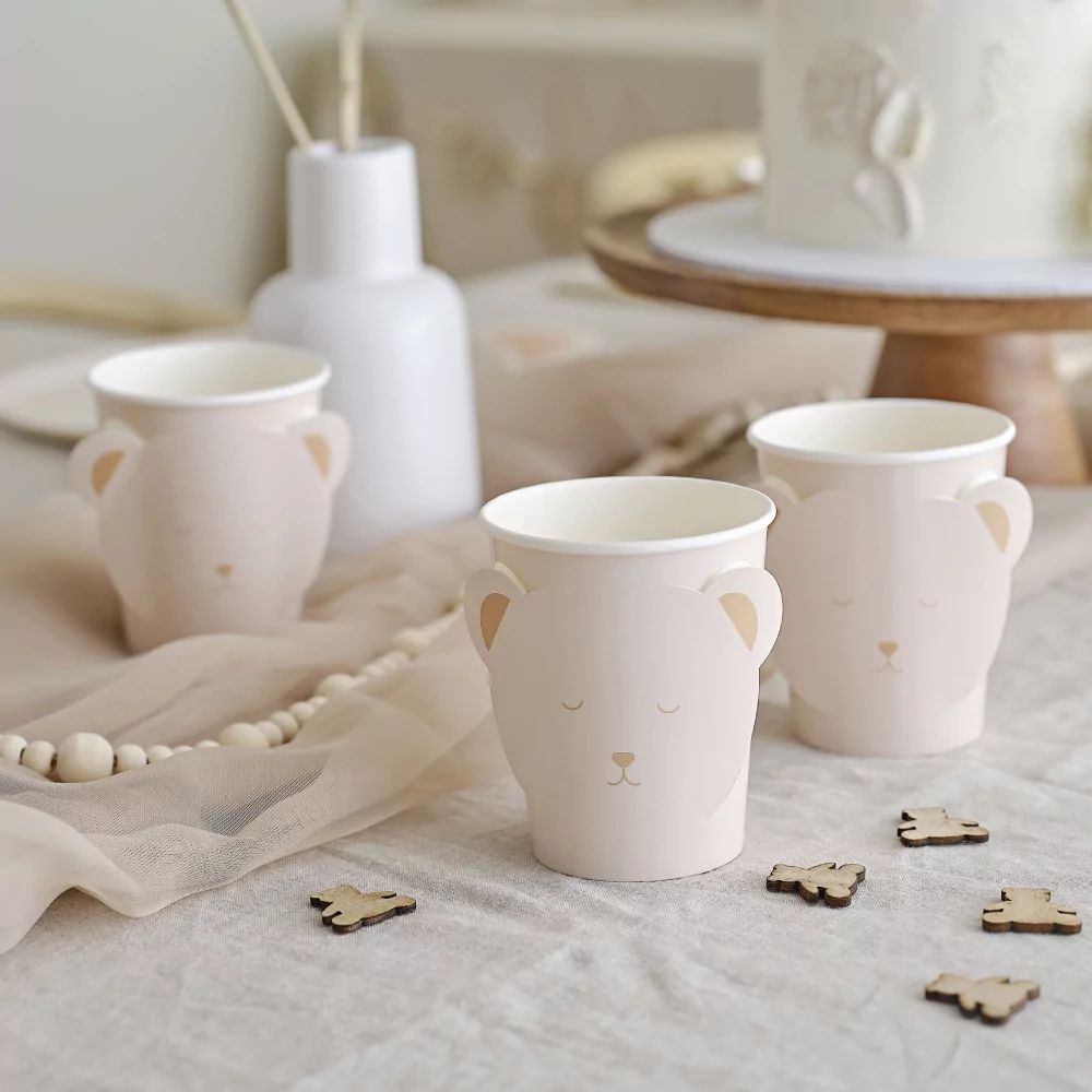 Bekers met een beren gezicht erop staan op een wit kleed met houten confetti