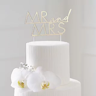 Gouden cake topper van acryl met de tekst mr and mrs zit in een witte taart met bloemen