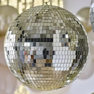 Gouden discobal hangt voor een beige ballonnenboog en gouden backdrop