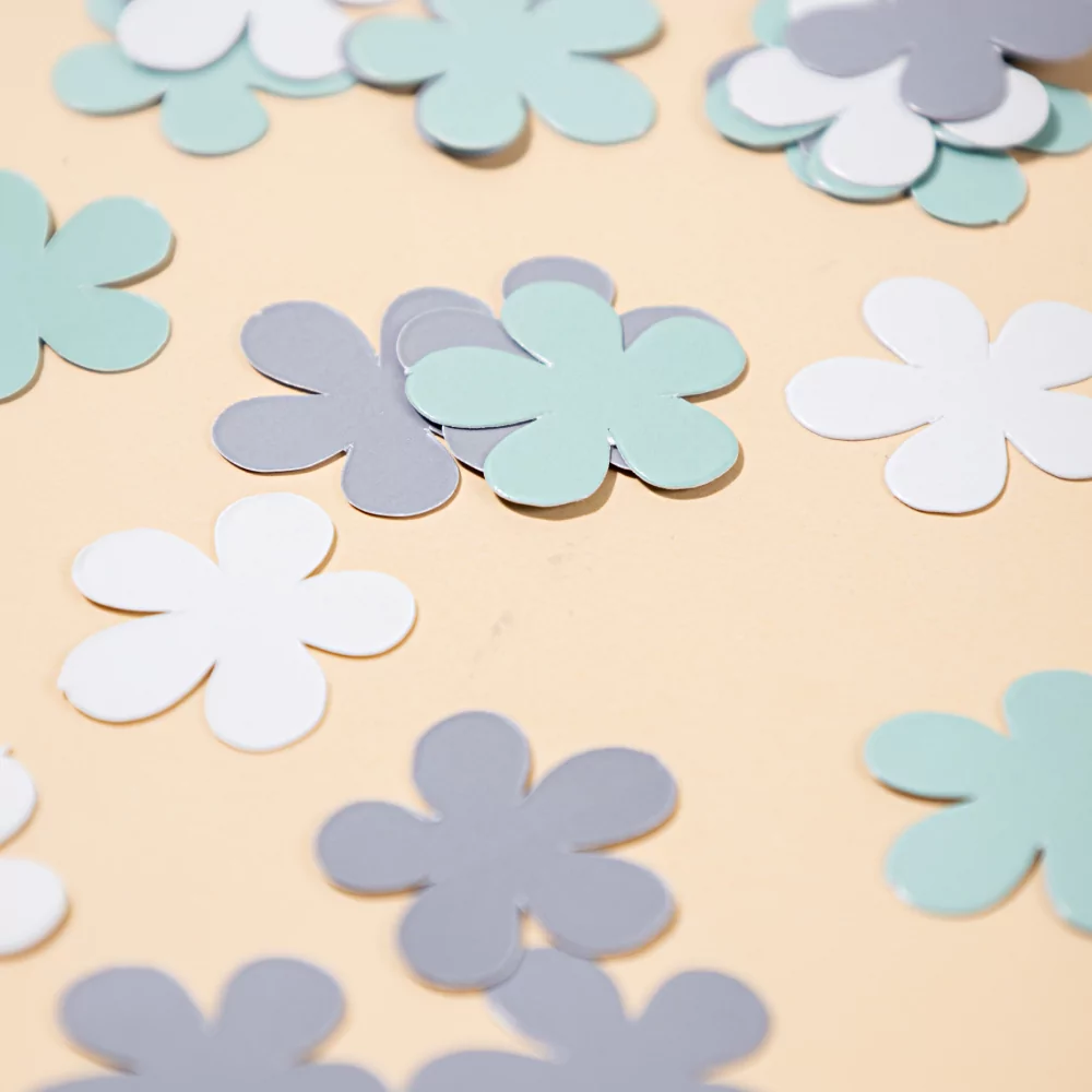 blauwe en witte confetti bloemen liggen op een gele ondergrond