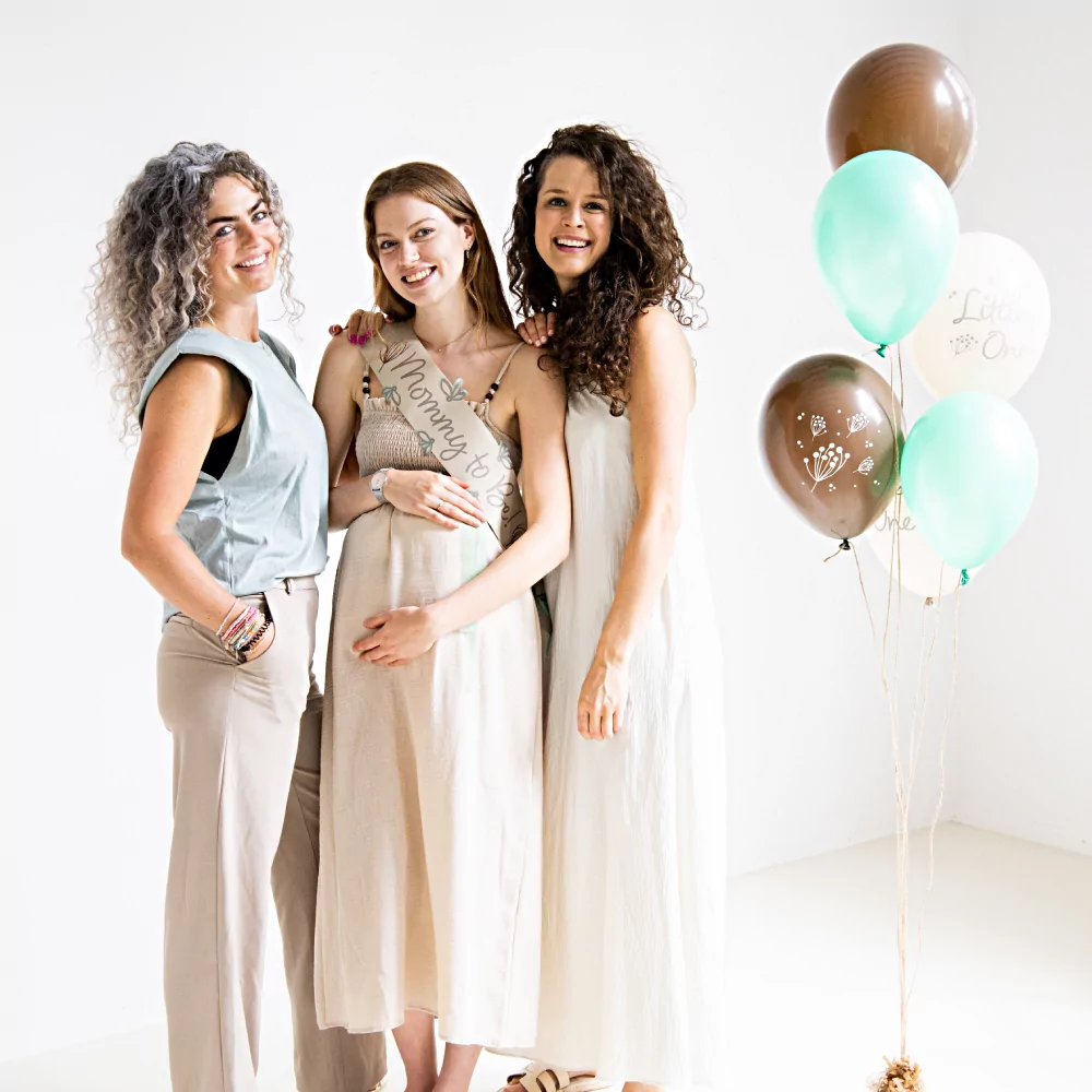 Drie vrouwen poseren tijdens een babyshower met een set ballonnen met mint, grijs en creme ballonnen