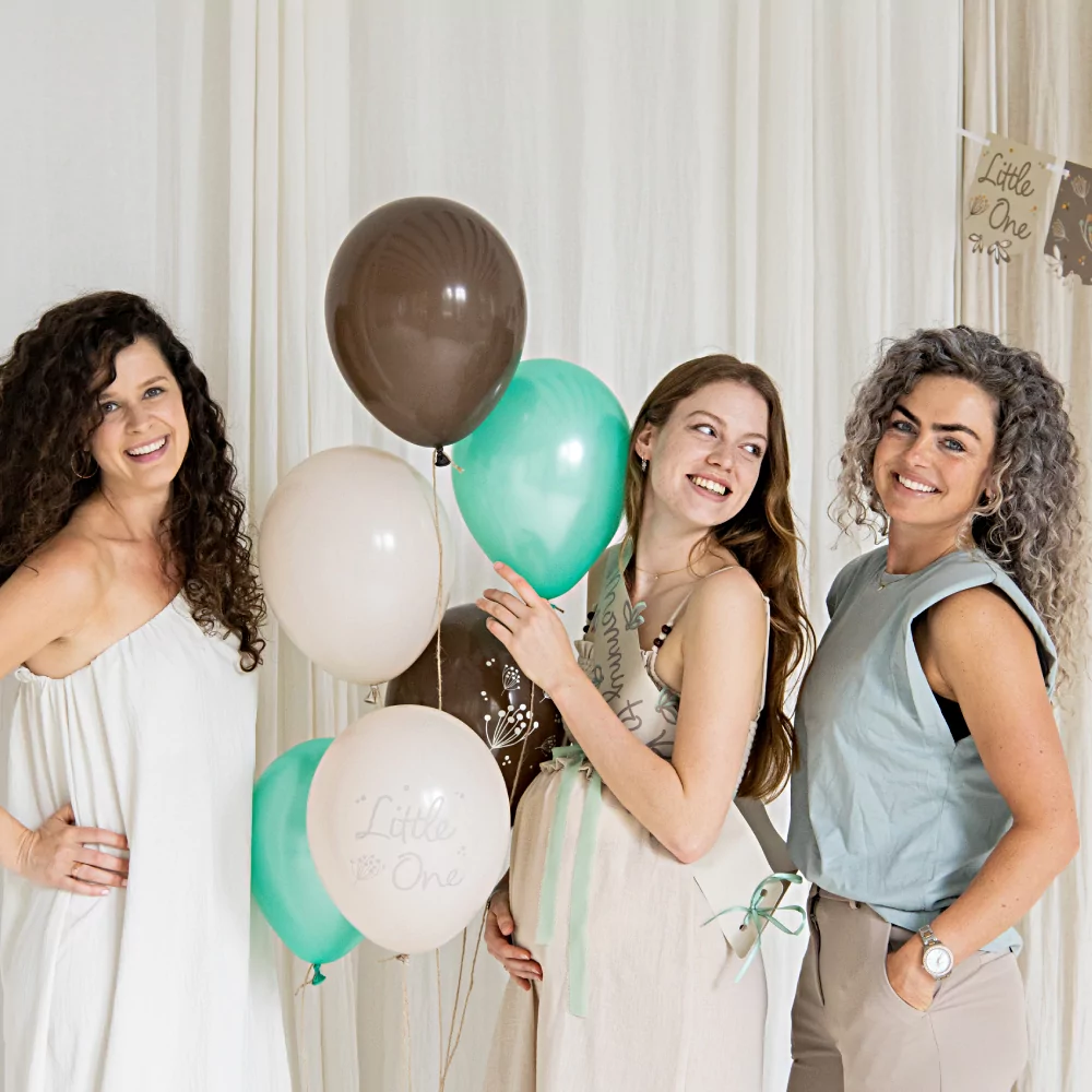 Drie vrouwen poseren tijdens een babyshower met een set ballonnen met mint, grijs en creme ballonnen