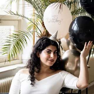vrouw met een zwarte en creme ballon met de tekst happy birthday