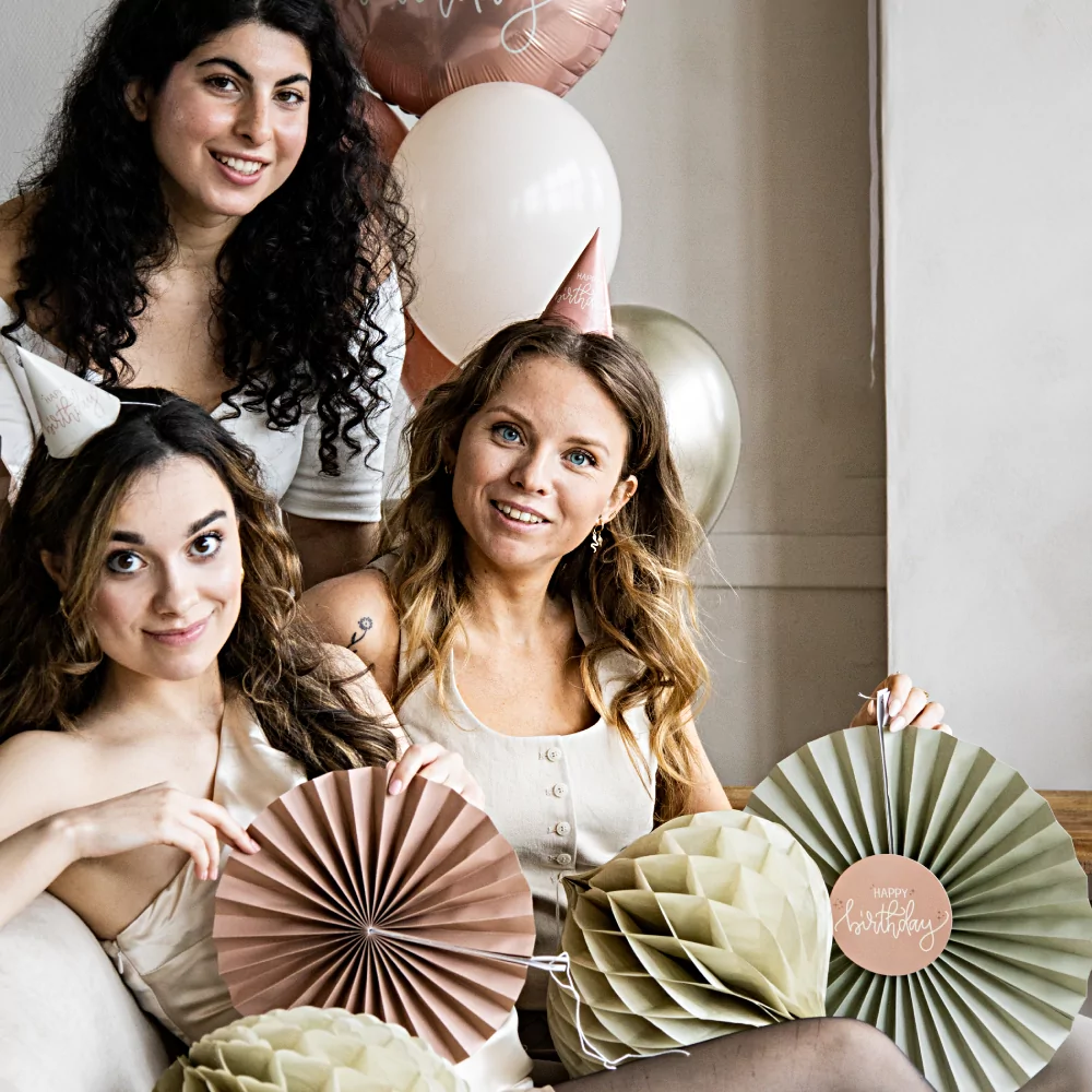 drie vrouwen omrings door cremekleurige honeycombs en roze waaiers