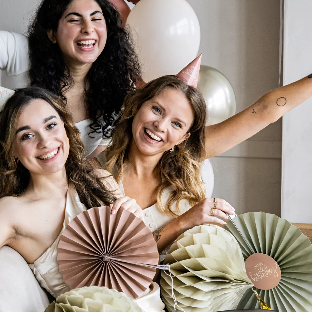drie vrouwen omrings door cremekleurige honeycombs en roze waaiers