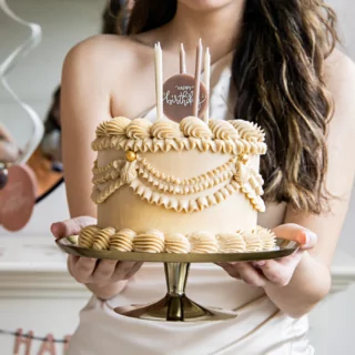 creme taart met roze en cremekleurige kaarsen met de tekst happy birthday