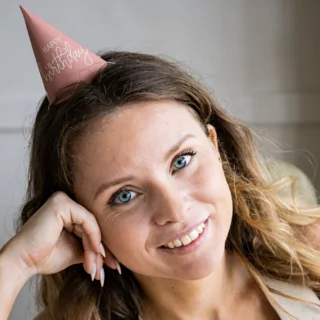 vrouw met een roze feesthoedje met de tekst happy birthday