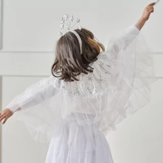 meisje met een hoofdband met sterren en een toverstaf draagt een witte tule cape met zilveren pailletten