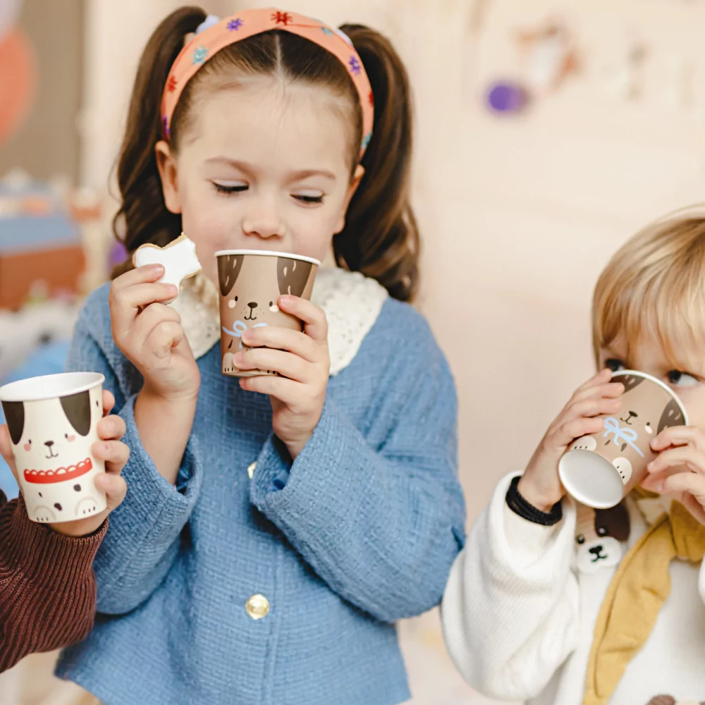 kinderen drinken uit bekers met puppies erop