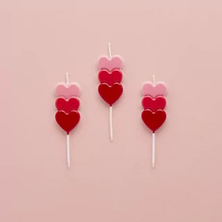 kaarsjes met rode, wijnrode en roze hartjes op een roze achtergrond