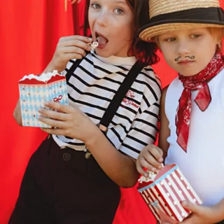 twee jongetjes in verkleedkleding heben circus popconbakjes vast