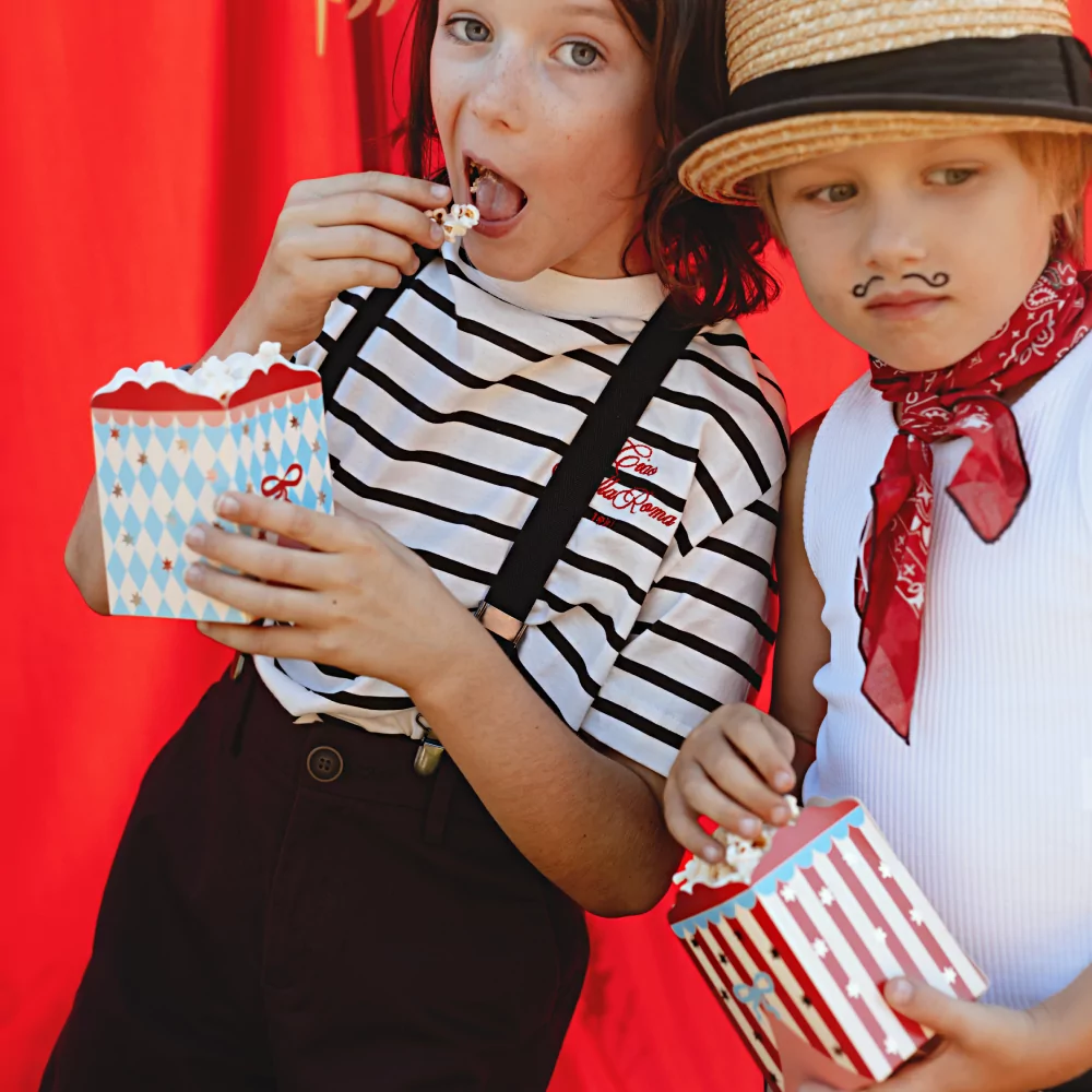 twee jongetjes in verkleedkleding heben circus popconbakjes vast