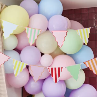 pastel vlaggetjes met ribbelrand hangt voor een pastel ballonnenboog