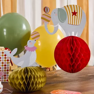 rode honeycomb met een olifant en gele honeycomb met een zeehond staan op een bruine tafel bij een circus feestje